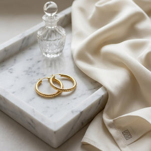 14K Yellow Gold Textured Hoop Earrings, on marble vanity tray with silk