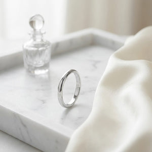 2mm Slightly Domed Traditional Oval Wedding Band in 18K White Gold, on marble vanity tray with silk