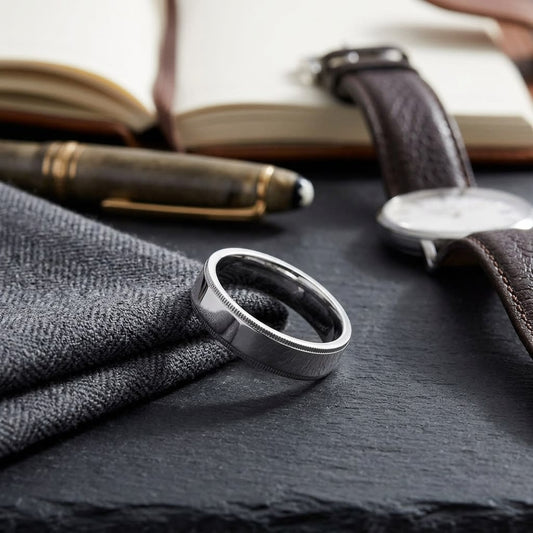 6mm Flat Milgrain Comfort-Fit Wedding Band in 18K White Gold, on walnut surface with pocket square