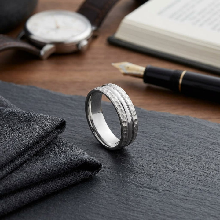 7.5mm Hammered Finish Carved Wedding Band in 18K White Gold, on walnut surface with pocket square