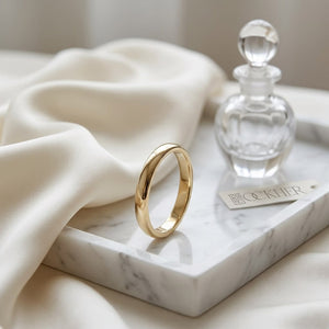 2mm Slightly Domed Traditional Oval Wedding Band in 18K Yellow Gold, on marble vanity tray with silk