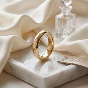 4mm Slightly Domed Traditional Oval Wedding Band in 18K Yellow Gold, on marble vanity tray with silk