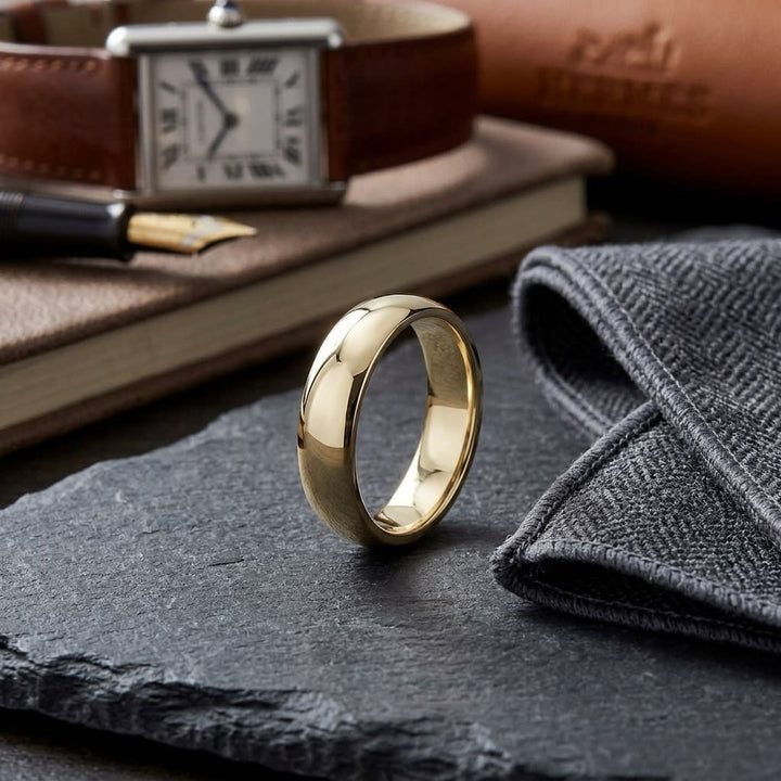 5mm Slightly Domed Traditional Oval Wedding Band in 18K Yellow Gold, on walnut surface with pocket square