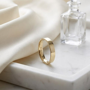 4mm Flat Comfort-Fit Wedding Band in 18K Yellow Gold, on marble vanity tray with silk