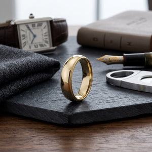 6mm Slightly Domed Milgrain Comfort-Fit Wedding Band in 18K Yellow Gold, on walnut surface with pocket square