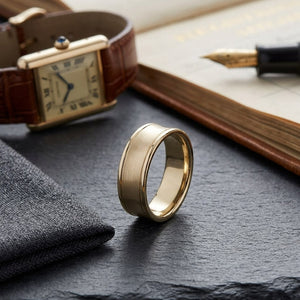 7.5mm Satin Finish High Polished Round Edge Carved Wedding Band in 18K Yellow Gold, on walnut surface with pocket square