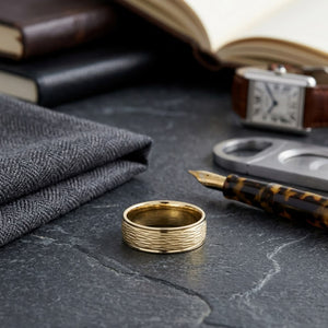 7.5mm Comfort-Fit Wedding Band in 18K Yellow Gold, on walnut surface with pocket square