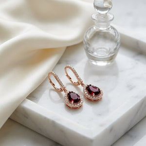 Rhodolite Garnet And Diamond Teardrop Halo Dangling Earrings in 14K Rose Gold, on marble vanity tray with silk