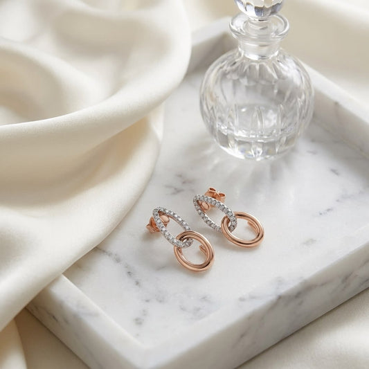 Diamond Pave And High Polish Teardrop Interlink Earrings in 14K Rose Gold, on marble vanity tray with silk