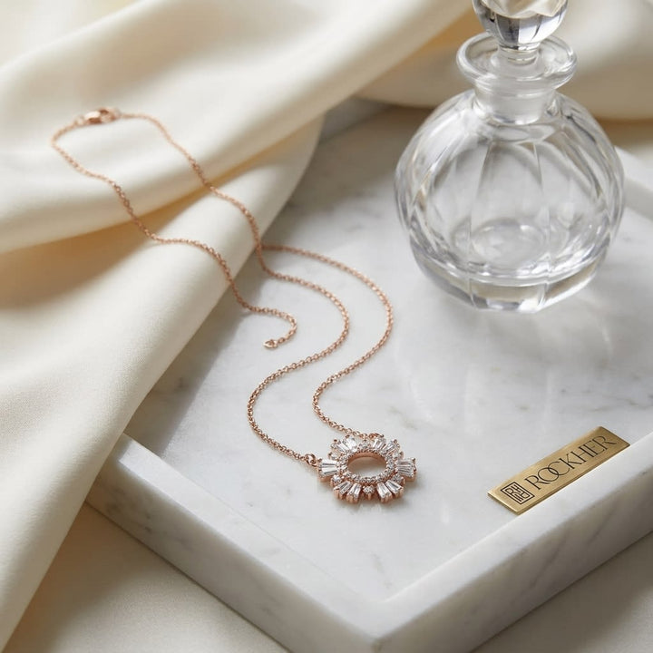 Diamond Pave Circle And Tapered Baguette Starburst Necklace in 14K Rose Gold, on marble vanity tray with silk