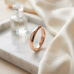 2mm Slightly Domed Traditional Oval Wedding Band in 14K Rose Gold, on marble vanity tray with silk