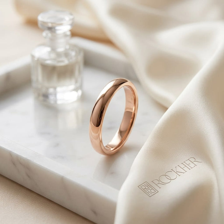2mm Slightly Domed Traditional Oval Wedding Band in 14K Rose Gold, on marble vanity tray with silk