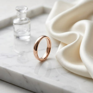 2.5mm Slightly Domed Traditional Oval Wedding Band in 14K Rose Gold, on marble vanity tray with silk