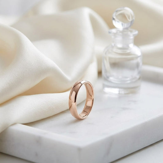 4mm Slightly Domed Traditional Oval Wedding Band in 14K Rose Gold, on marble vanity tray with silk