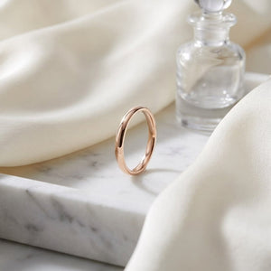 2.5mm Slightly Domed Comfort-Fit Wedding Band in 14K Rose Gold, on marble vanity tray with silk