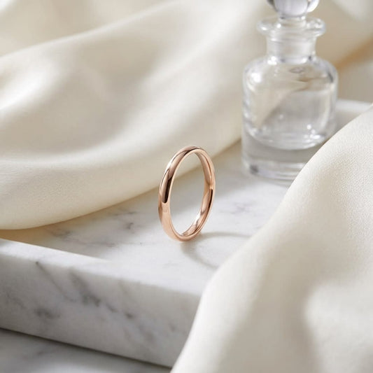 2.5mm Slightly Domed Comfort-Fit Wedding Band in 14K Rose Gold, on marble vanity tray with silk
