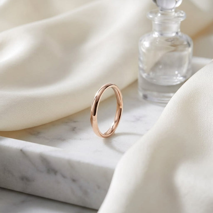 2.5mm Slightly Domed Comfort-Fit Wedding Band in 14K Rose Gold, on marble vanity tray with silk