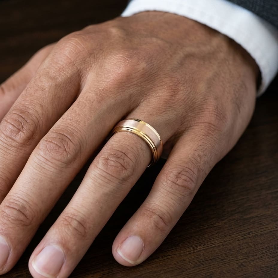 8mm Satin Finish Carved Wedding Band in 14K Rose Gold, worn on hand, masculine close-up
