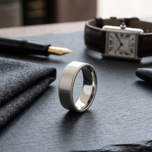 8mm Satin Finish Carved Wedding Band in 14K Rose Gold, on walnut surface with pocket square