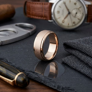 7mm Round Edge Swirl Finish Carved Wedding Band in 14K Rose Gold, on walnut surface with pocket square