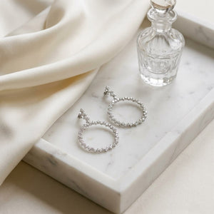 Scattered Diamonds Circle Earrings in 14k White Gold 3.38ctw, on marble vanity tray with silk