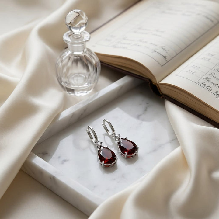 Garnet Pear And Diamond Earrings in 14K White Gold, on marble vanity tray with silk