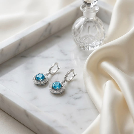 Blue Topaz And Diamond Swirl Dangling Earrings in 14K White Gold, on marble vanity tray with silk