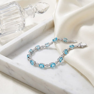 Blue Topaz Oval Half-bezel And Diamond Pave East-west Bracelet in 14K White Gold, on marble vanity tray with silk