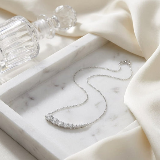 Diamond Round Graduated Prong-set Comet Necklace in 14K White Gold, on marble vanity tray with silk