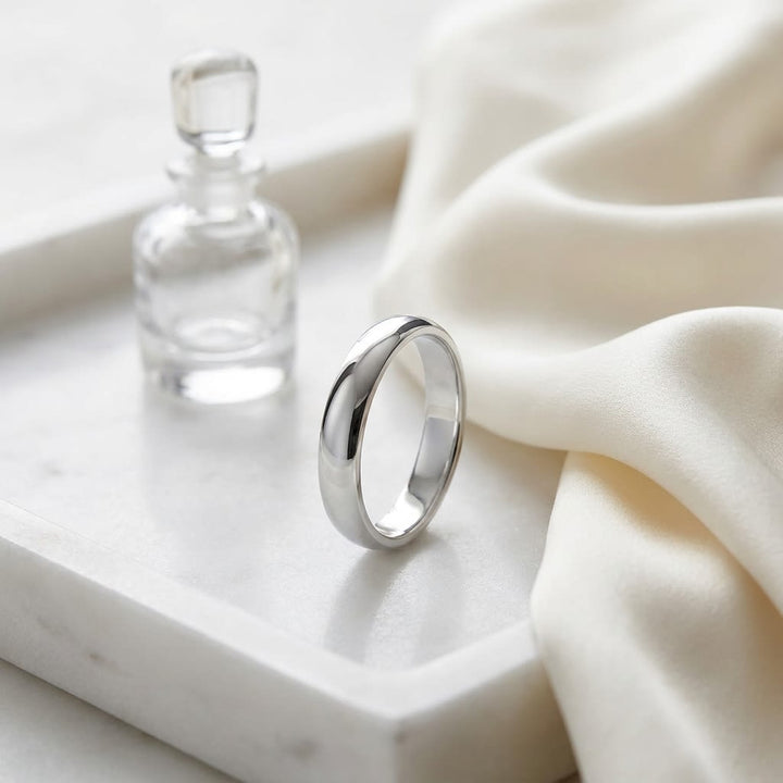 4mm Slightly Domed Traditional Oval Wedding Band in 14K White Gold, on marble vanity tray with silk