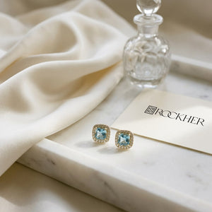 Swiss Blue Topaz and Diamond Earrings in 14K Yellow Gold, 0.20ct, on marble vanity tray with silk