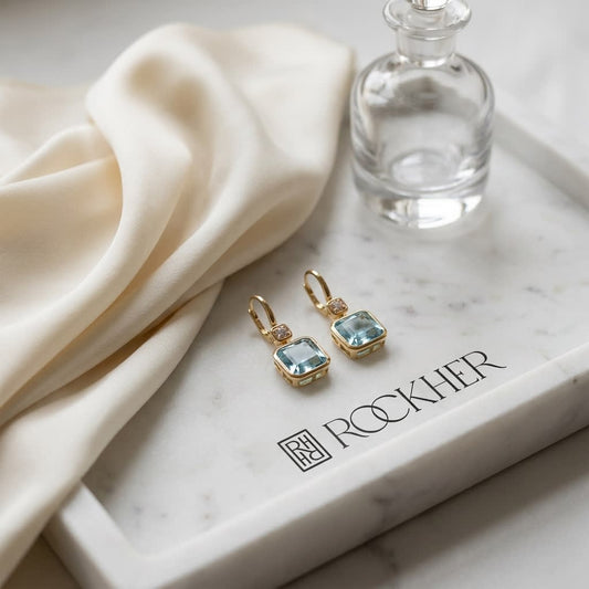 Swiss Blue Topaz Bezel Earrings in 14k Yellow Gold 0.08ctw, on marble vanity tray with silk