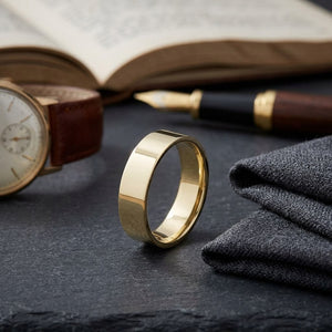 6mm Traditional Flat Wedding Band in 14K Yellow Gold, on walnut surface with pocket square