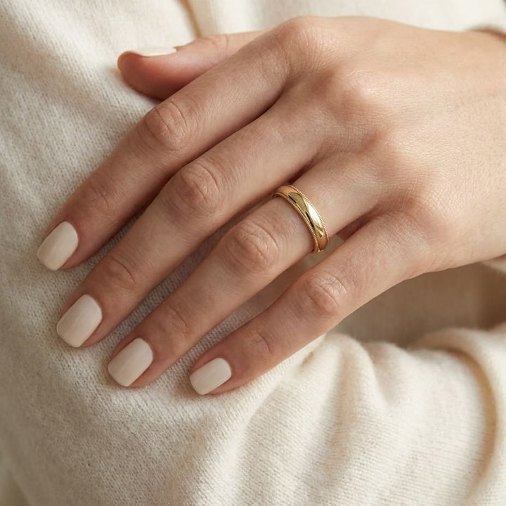 4mm Slightly Domed Traditional Oval Milgrain Wedding Band in 14K Yellow Gold, worn on hand, close-up
