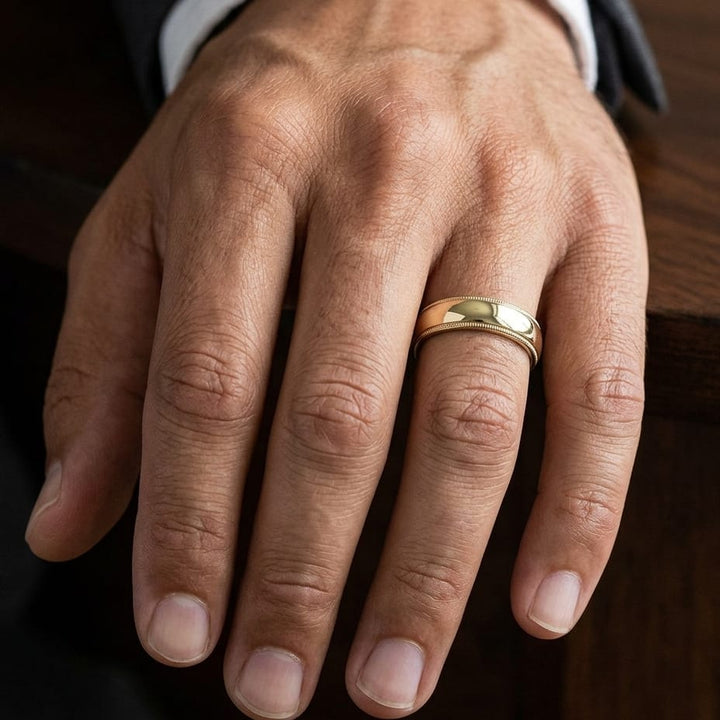 5mm Slightly Domed Traditional Oval Milgrain Wedding Band in 14K Yellow Gold, worn on hand, masculine close-up