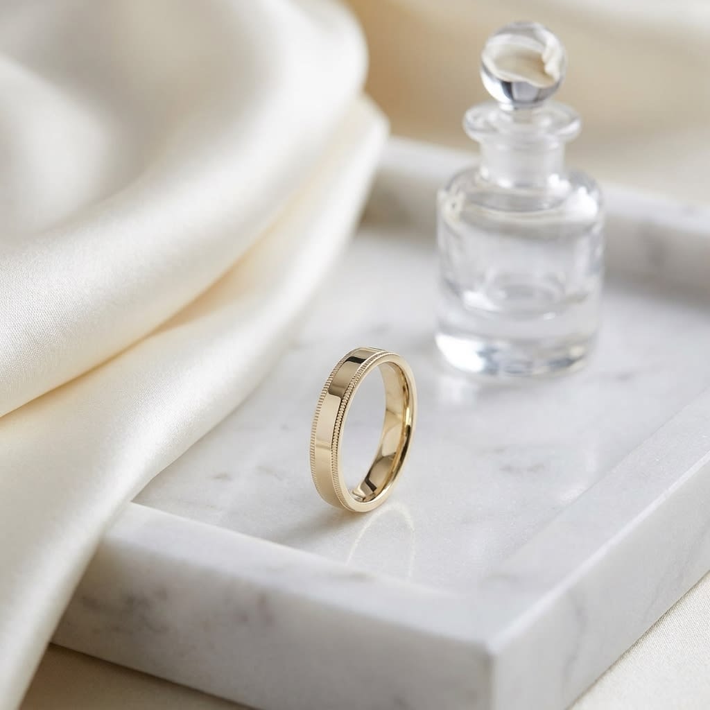 4mm Flat Milgrain Comfort-Fit Wedding Band in 14K Yellow Gold, on marble vanity tray with silk