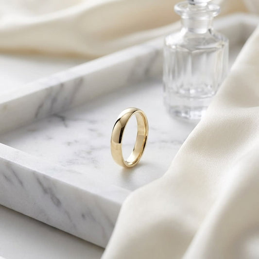 4mm Low Dome Wedding Band in 14K Yellow Gold, on marble vanity tray with silk