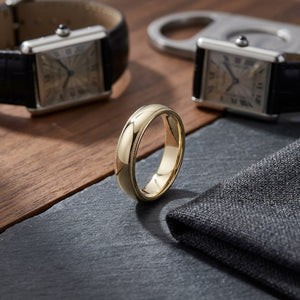 5mm Slightly Domed Milgrain Comfort-Fit Wedding Band in 14K Yellow Gold, on walnut surface with pocket square