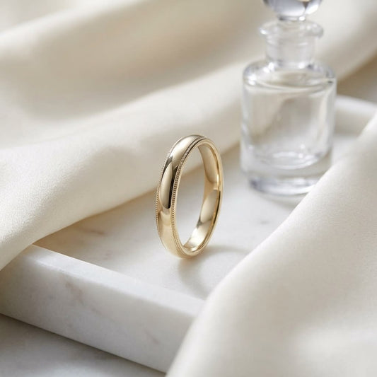 4mm Slightly Domed Super Light Milgrain Comfort-Fit Wedding Band in 14K Yellow Gold, on marble vanity tray with silk