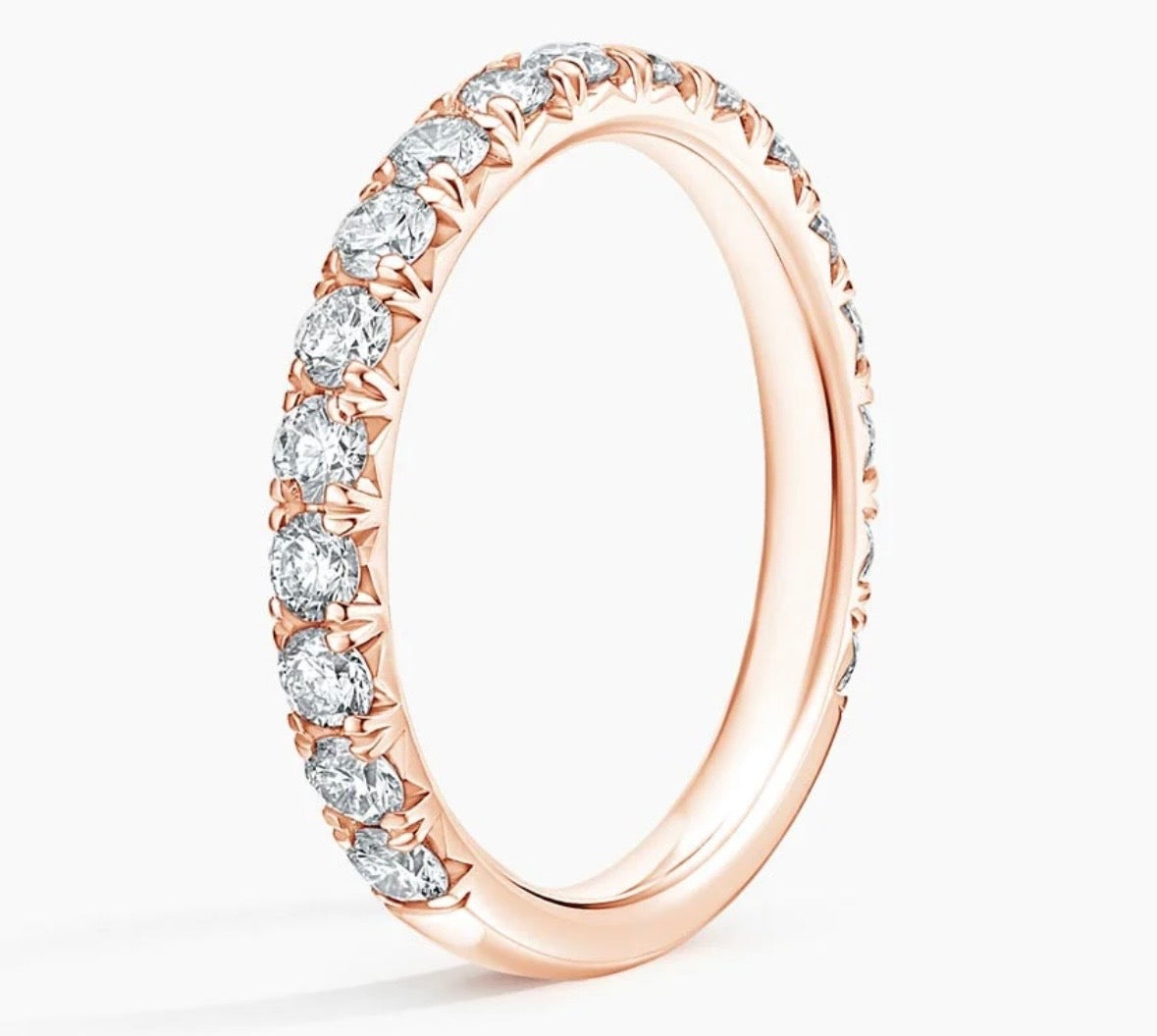 A rose gold eternity ring featuring a continuous row of round-cut clear gemstones in a prong setting, shown on a clean white background.