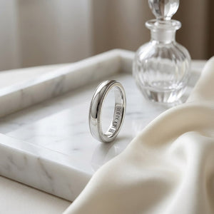 4mm Slightly Domed Traditional Oval Milgrain Wedding Band in Platinum, on marble vanity tray with silk