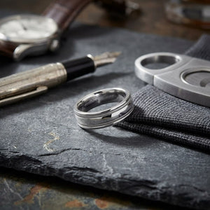6mm High Polish Milgrain Round Edge Carved Wedding Band in Platinum, on walnut surface with pocket square