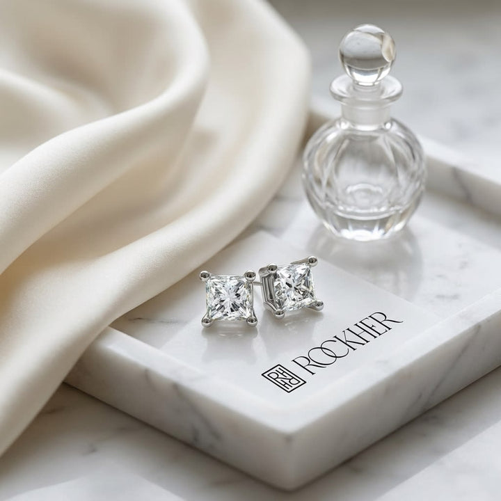 Natural Diamond Princess Cut Four Prong Stud Earrings in Platinum, 1/2 ct. t.w., on marble vanity tray with silk