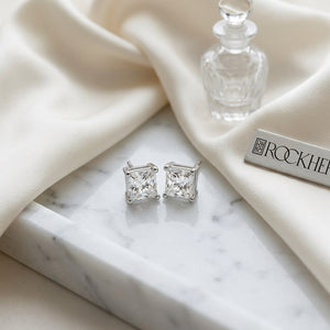Natural Diamond Princess Cut Four Prong Stud Earrings in Platinum, 1.1 ct. t.w., on marble vanity tray with silk