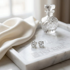 Natural Diamond Round Brilliant Four Prong Stud Earrings in Platinum, 1 ct. t.w., on marble vanity tray with silk