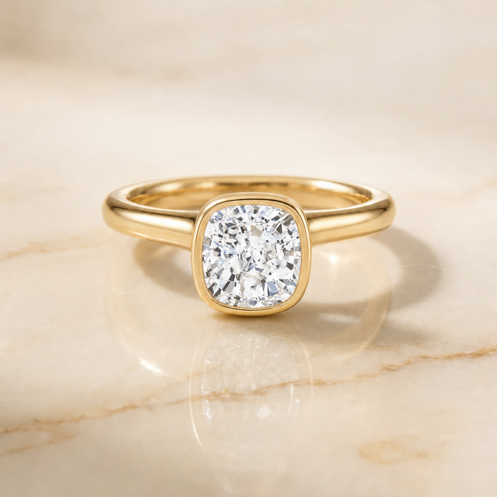 The Duran Simple Bezel Solitaire Cushion Cut Engagement Ring Setting in 18K Yellow Gold