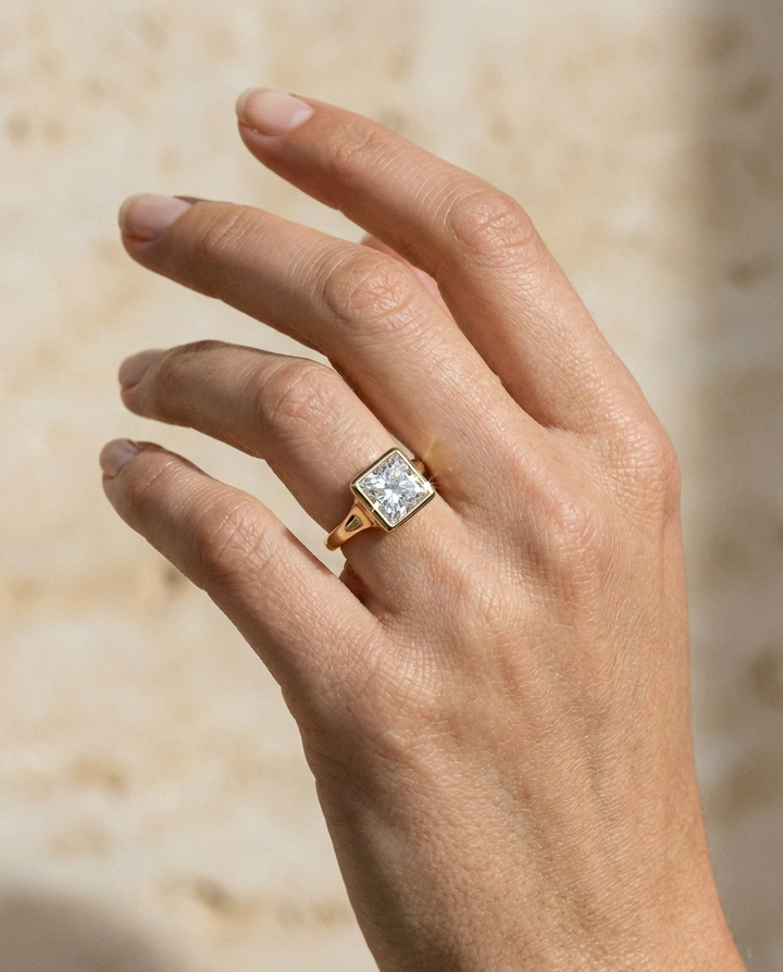 The Agnes Select bezel solitaire princess engagement ring in 18k yellow gold — on hand — RockHer