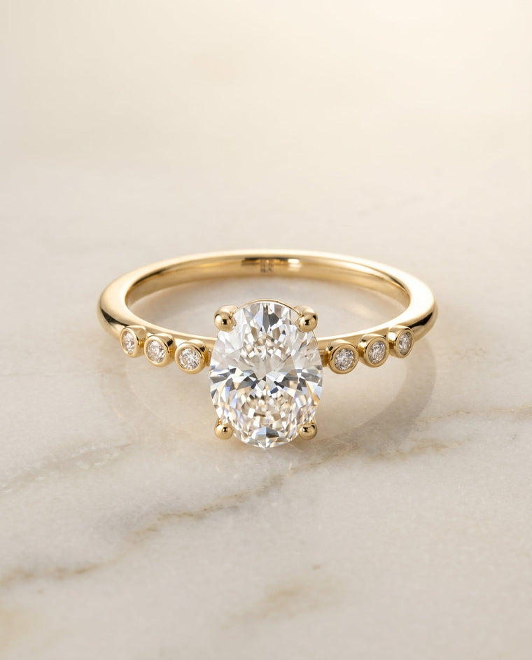 The Peggy Select Bezel Accent Solitaire Oval Lab Diamond Engagement Ring in 18K Yellow Gold
