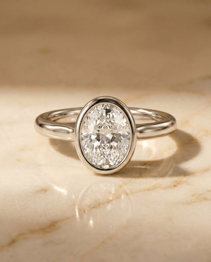 Agnes Select Bezel Solitaire In Oval Lab Diamond Engagement Ring in 18K White Gold, shown on hand, angled | RockHer
