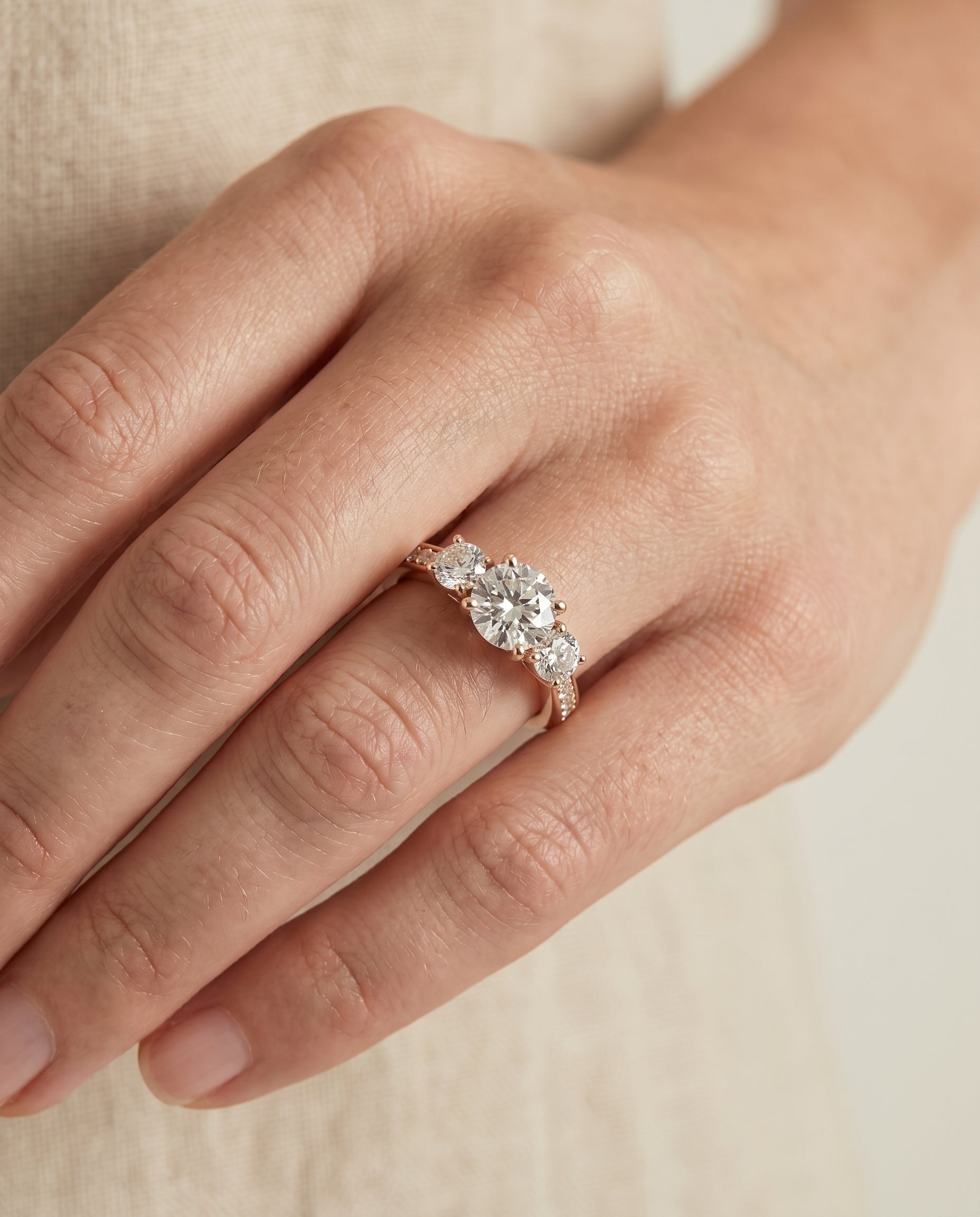Avery Select Channel Pavé Three Stone Round Lab Diamond Engagement Ring in 14K Rose Gold, shown on hand, angled | RockHer